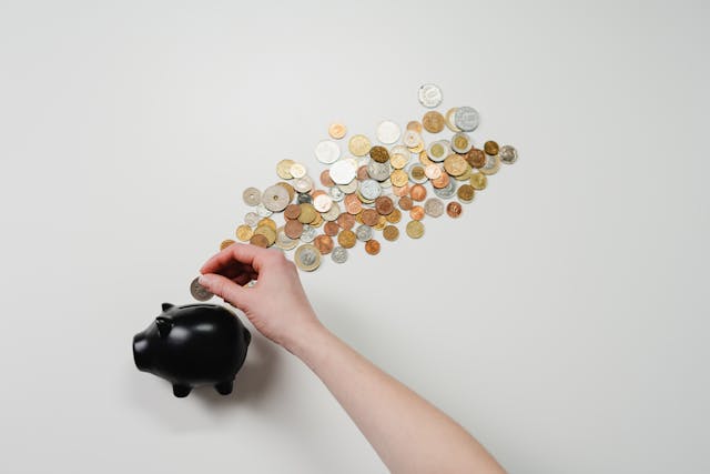 coins being put into a black piggy bank